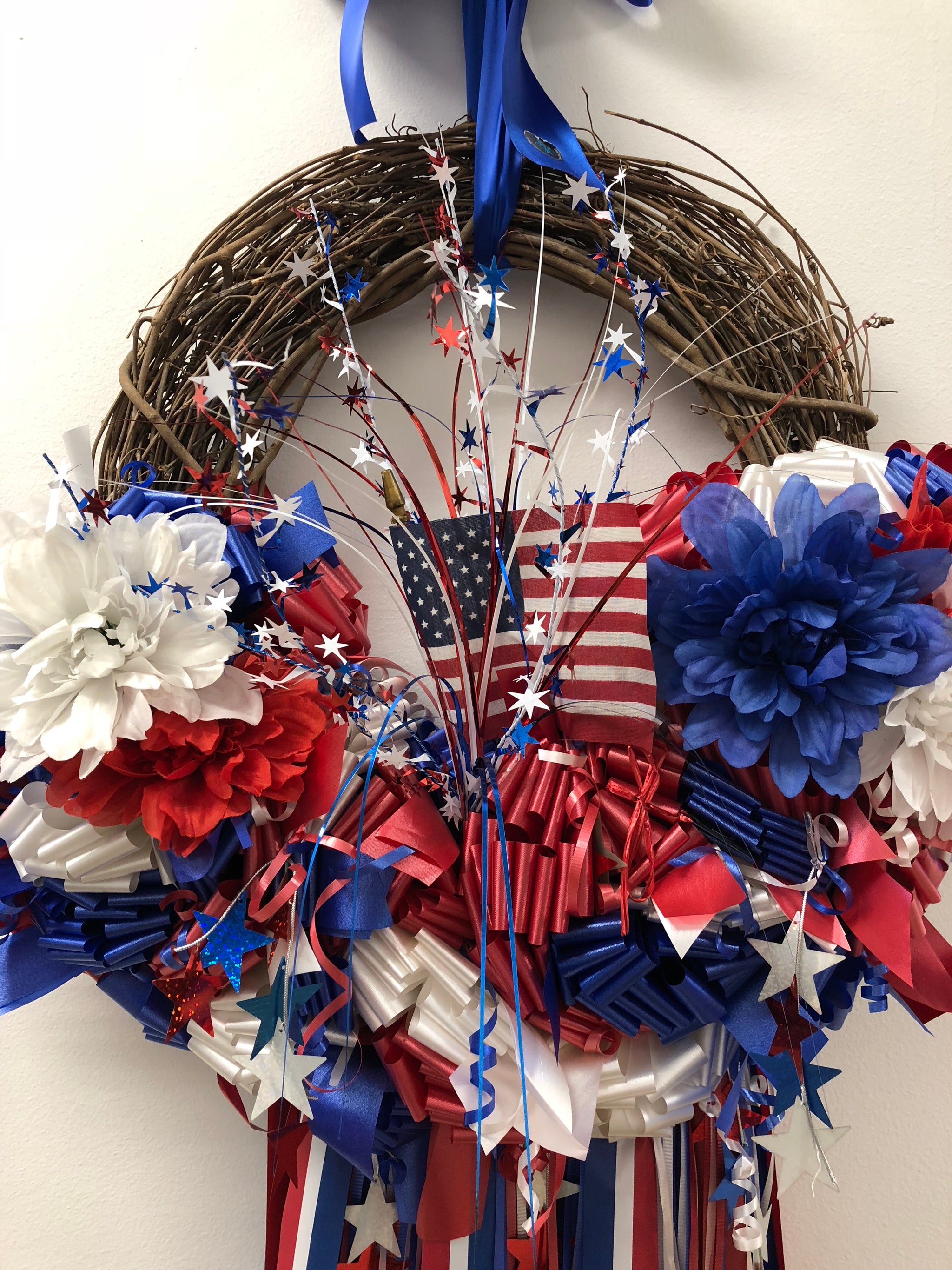 Red, White and Blue wreath with white Easel stand. Carnations, delphium and  white cushion poms with ribbons and stars. in Oxford, OH - OXFORD FLOWER  SHOP